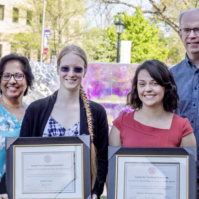 		Award winners holding framed certificates smiling at the camera with other people next to them also smiling
	